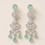 Pair of emerald and diamond earrings on a light beige background