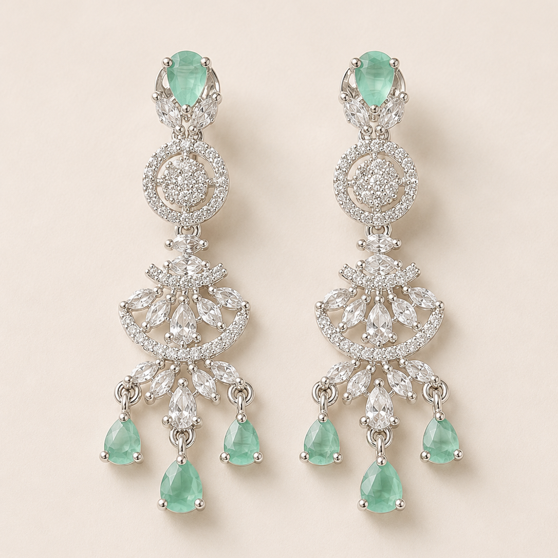 Pair of emerald and diamond earrings on a light beige background