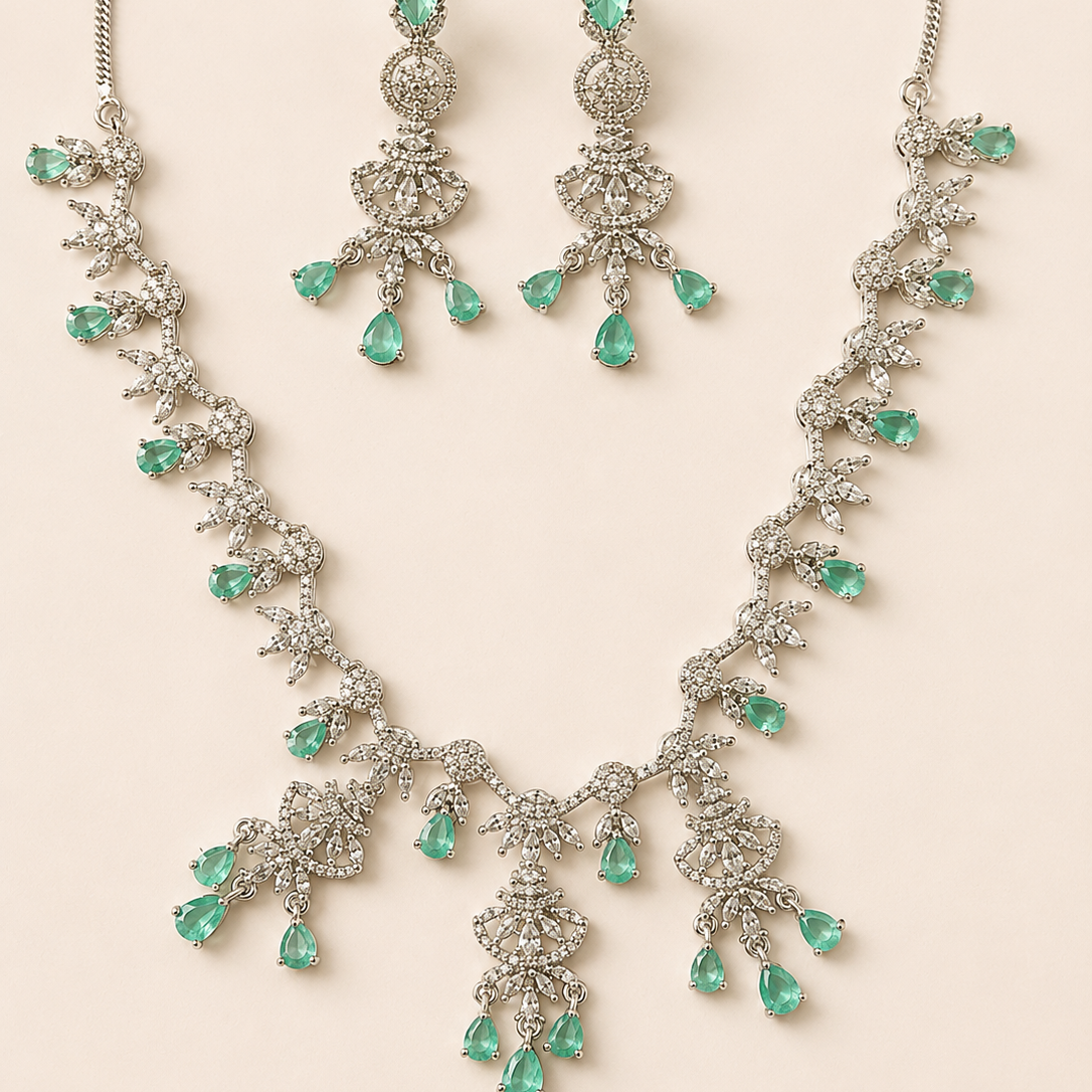 Jewelry set with necklace and earrings featuring emerald green stones on a beige background