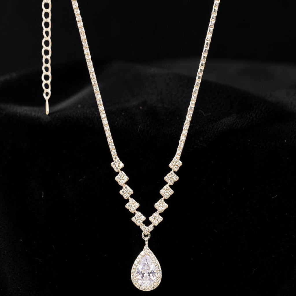Silver tone necklace with a teardrop pendant on a black background