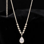 Silver tone necklace with a teardrop pendant on a black background
