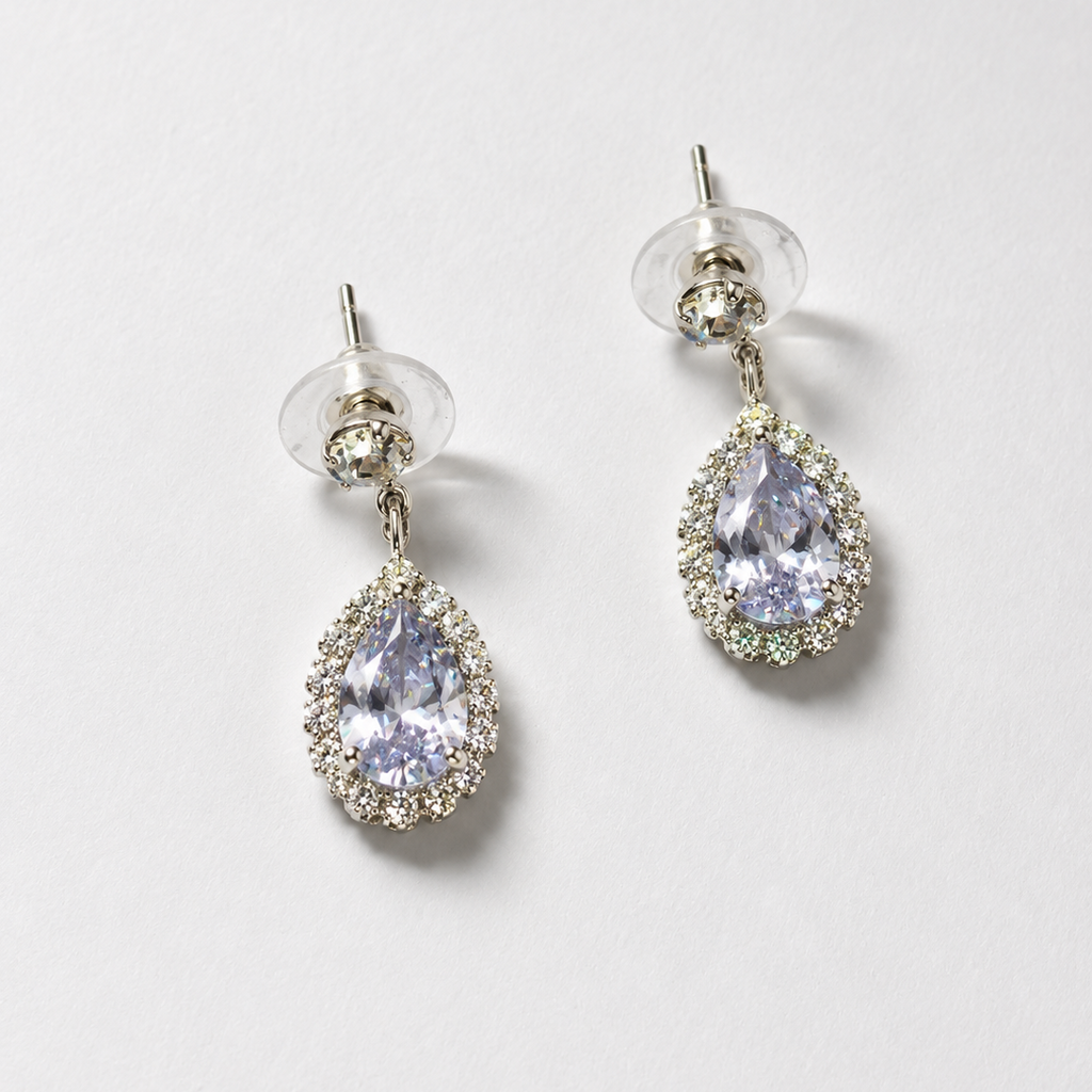 Pair of teardrop-shaped earrings with clear gemstones on a light gray background
