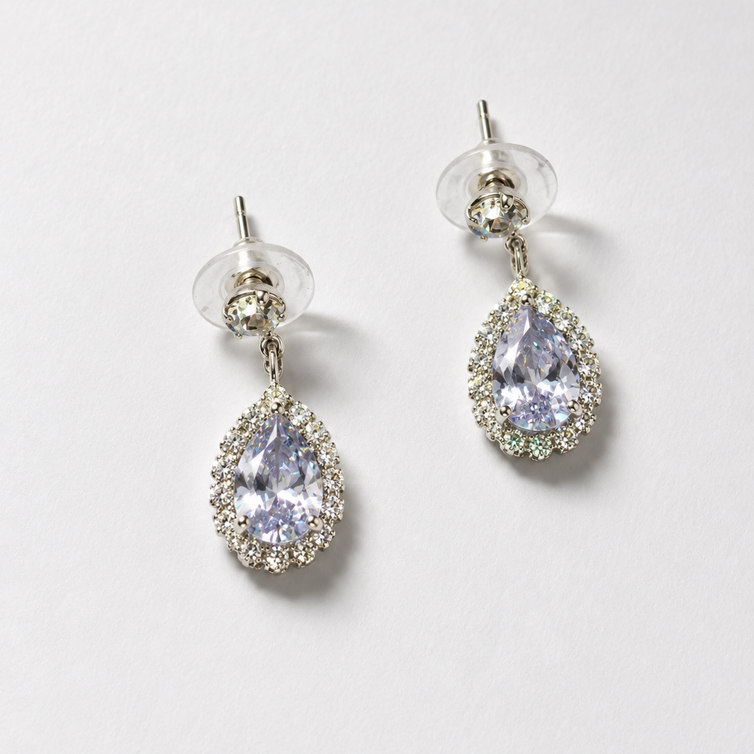Pair of teardrop-shaped earrings with clear gemstones on a light gray background