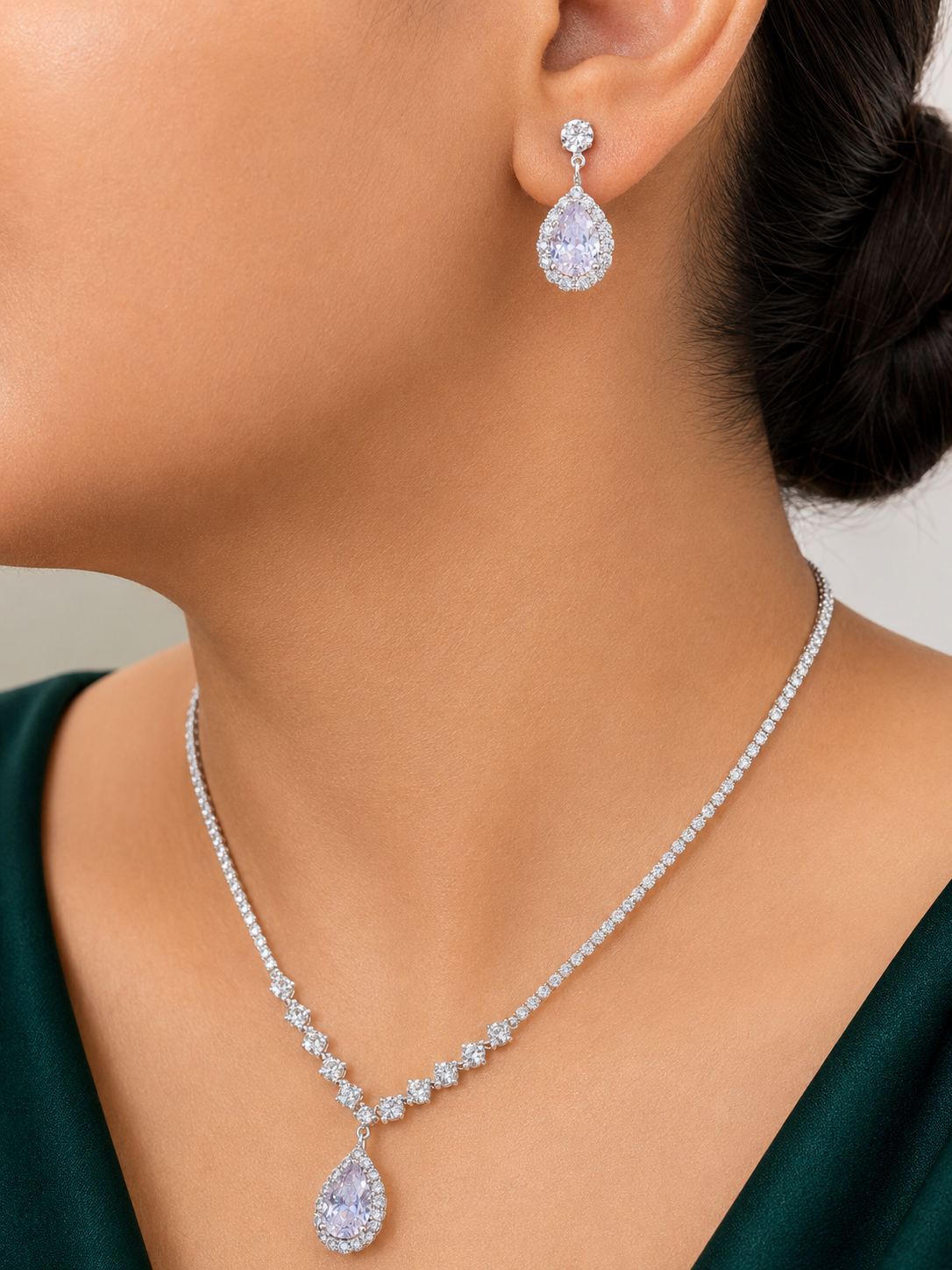 Close-up of a person wearing a diamond necklace and earrings against a neutral background