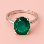 Silver ring with a green gemstone on a pink background
