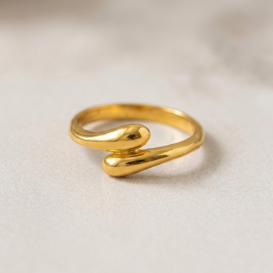 Gold tone ring with a wavy design on a beige background