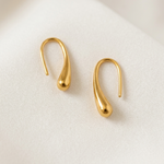 Pair of gold tone  earrings on a light beige background