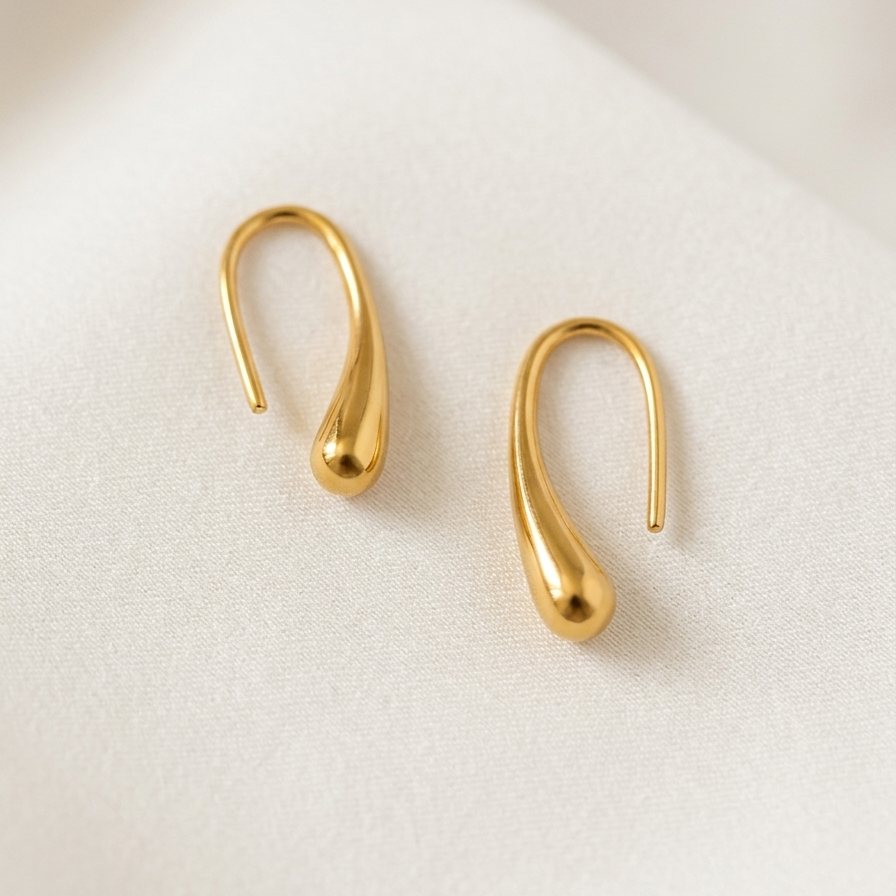 Pair of gold tone  earrings on a light beige background