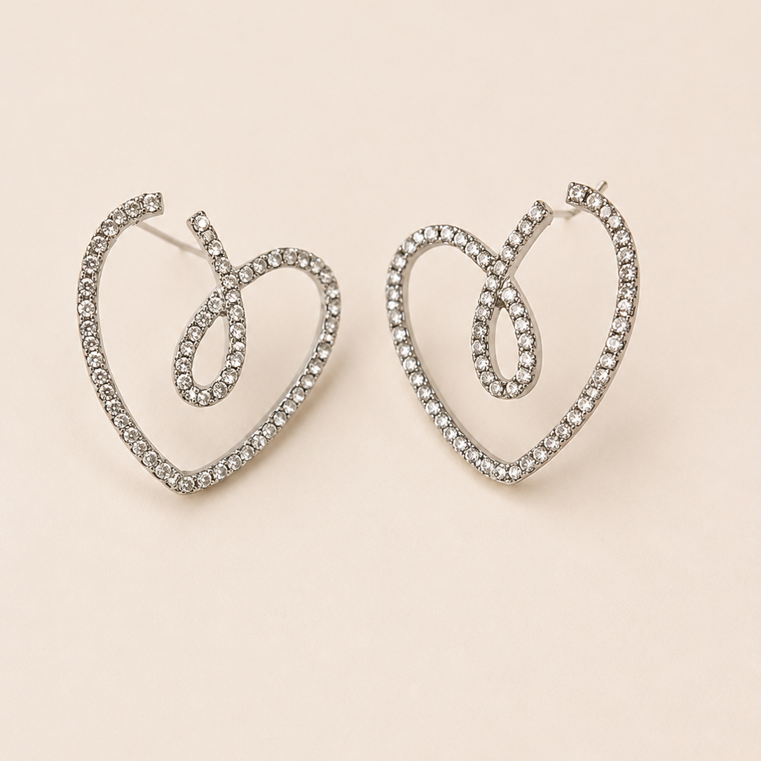 Heart-shaped earrings with rhinestones on a beige background