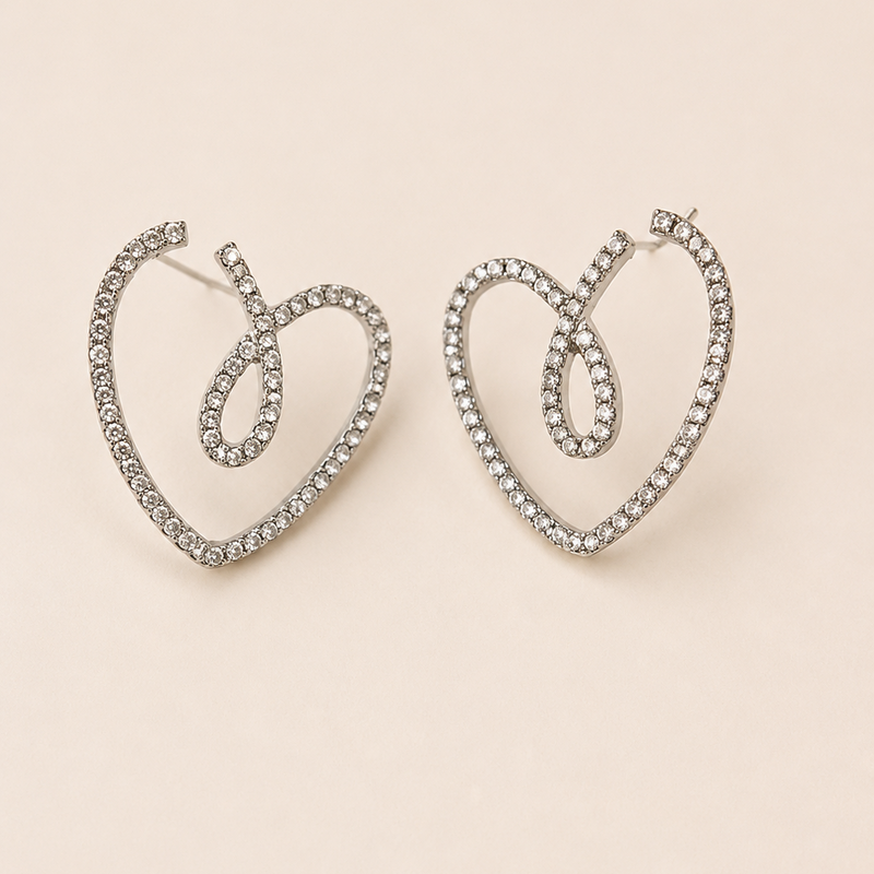 Heart-shaped earrings with rhinestones on a beige background