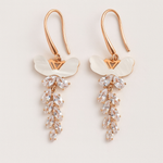 Pair of rose gold tone earrings with clear gemstones on a light background