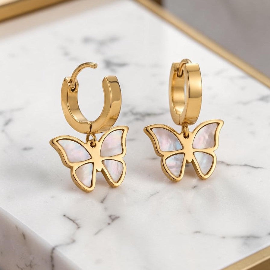 Golden butterfly earrings on a marble surface
