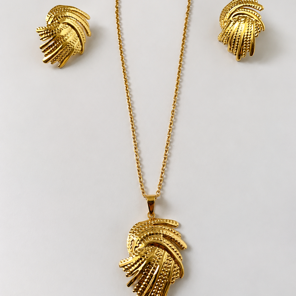 Gold tone necklace and earrings set on a light gray background