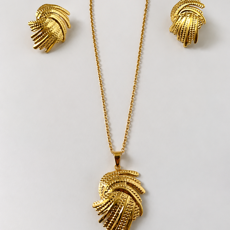 Gold tone necklace and earrings set on a light gray background