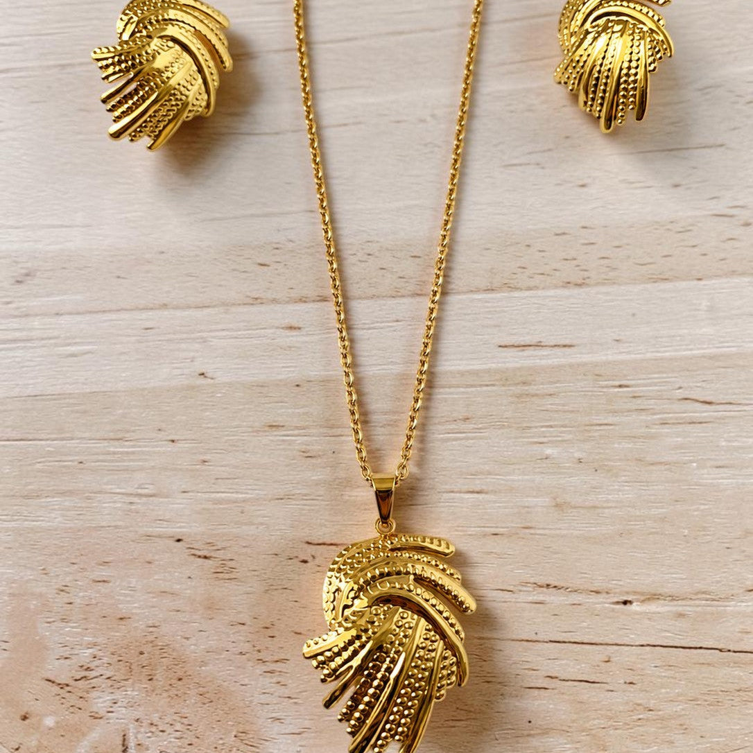 Gold tone necklace and earrings on a wooden surface