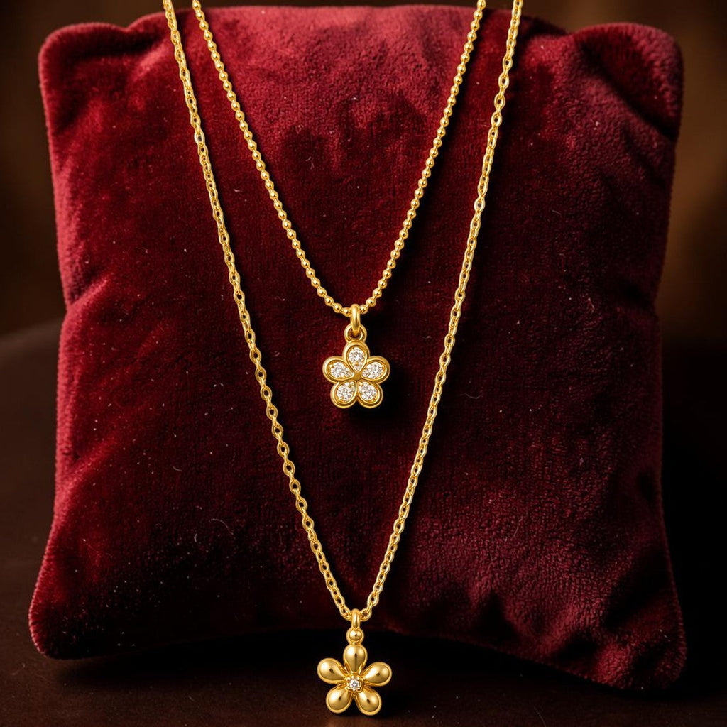 Gold tone necklaces with floral pendants on a red velvet cushion