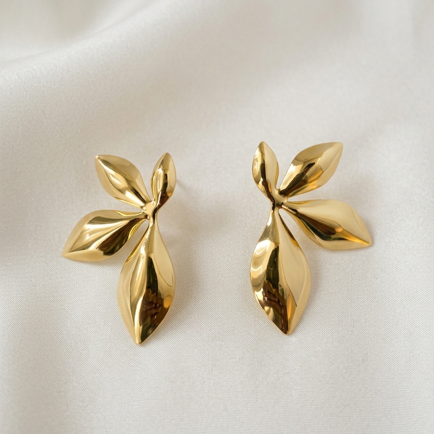 Pair of gold leaf-shaped earrings on a light background