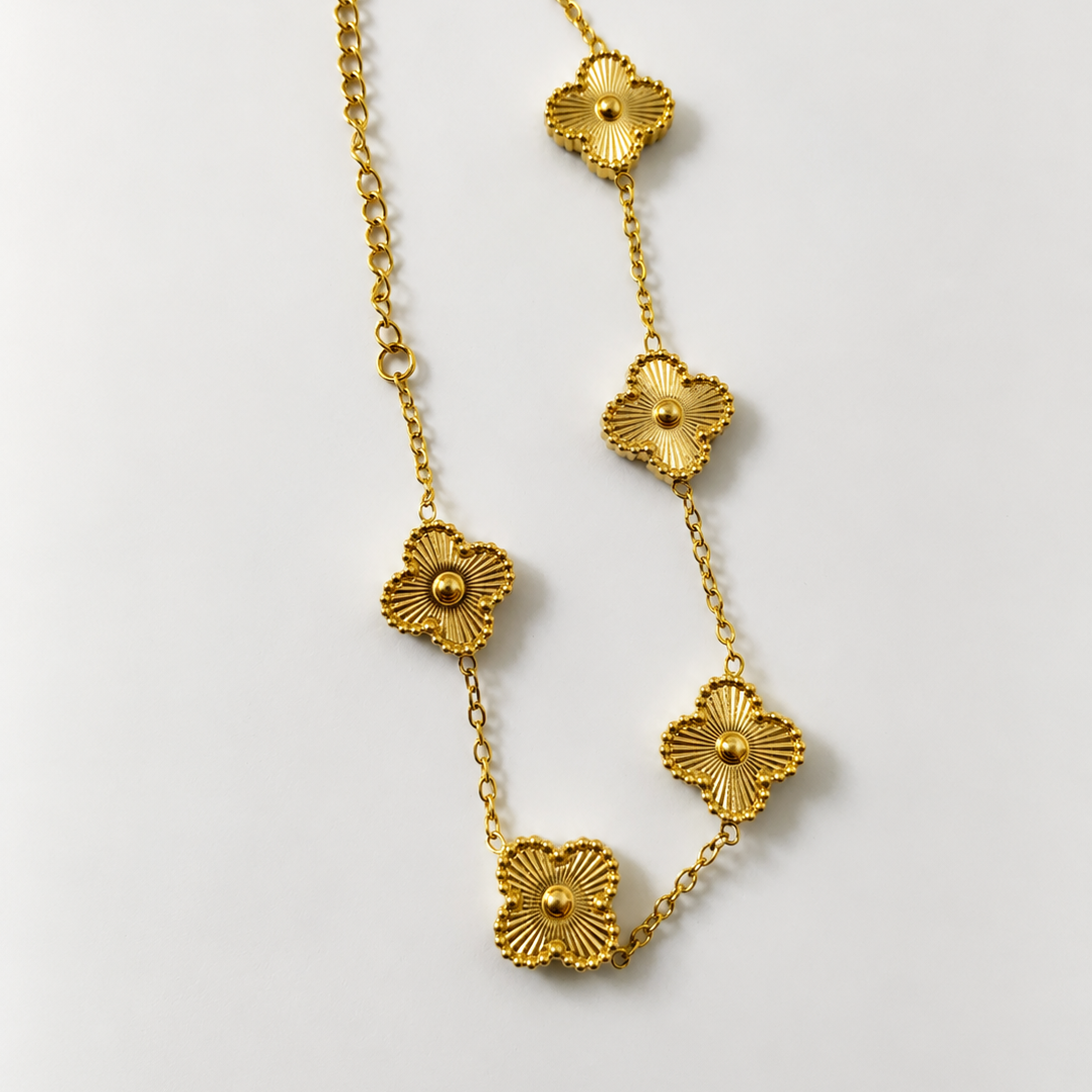 Gold tone necklace with floral designs on a light gray background
