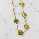 Gold tone necklace with floral designs on a marble background