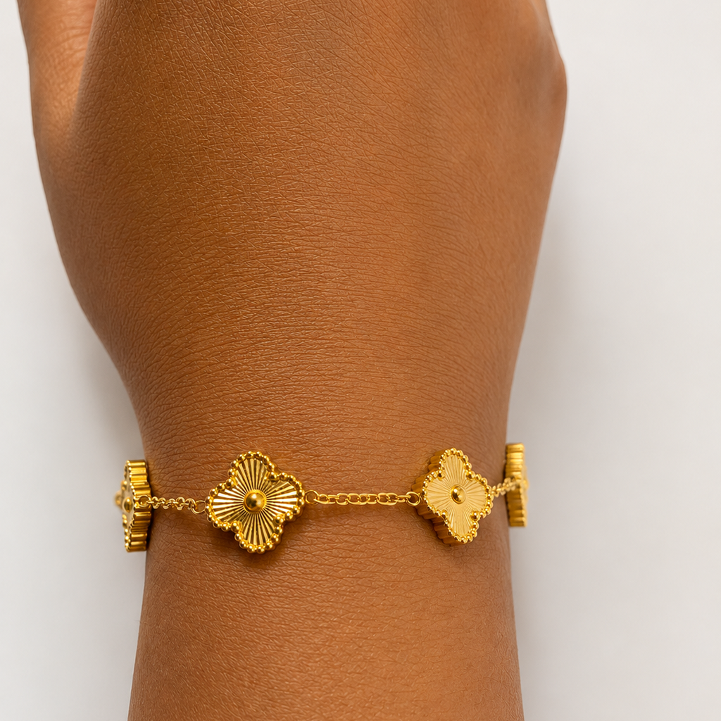 Gold tone bracelet on a wrist with a plain background