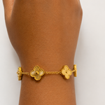 Gold tone bracelet on a wrist with a plain background