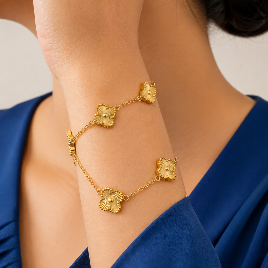 Gold tone bracelet with floral designs on a person wearing a blue dress.
