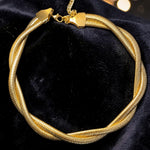 Gold tone bracelet on a black velvet surface with blurred lights in the background