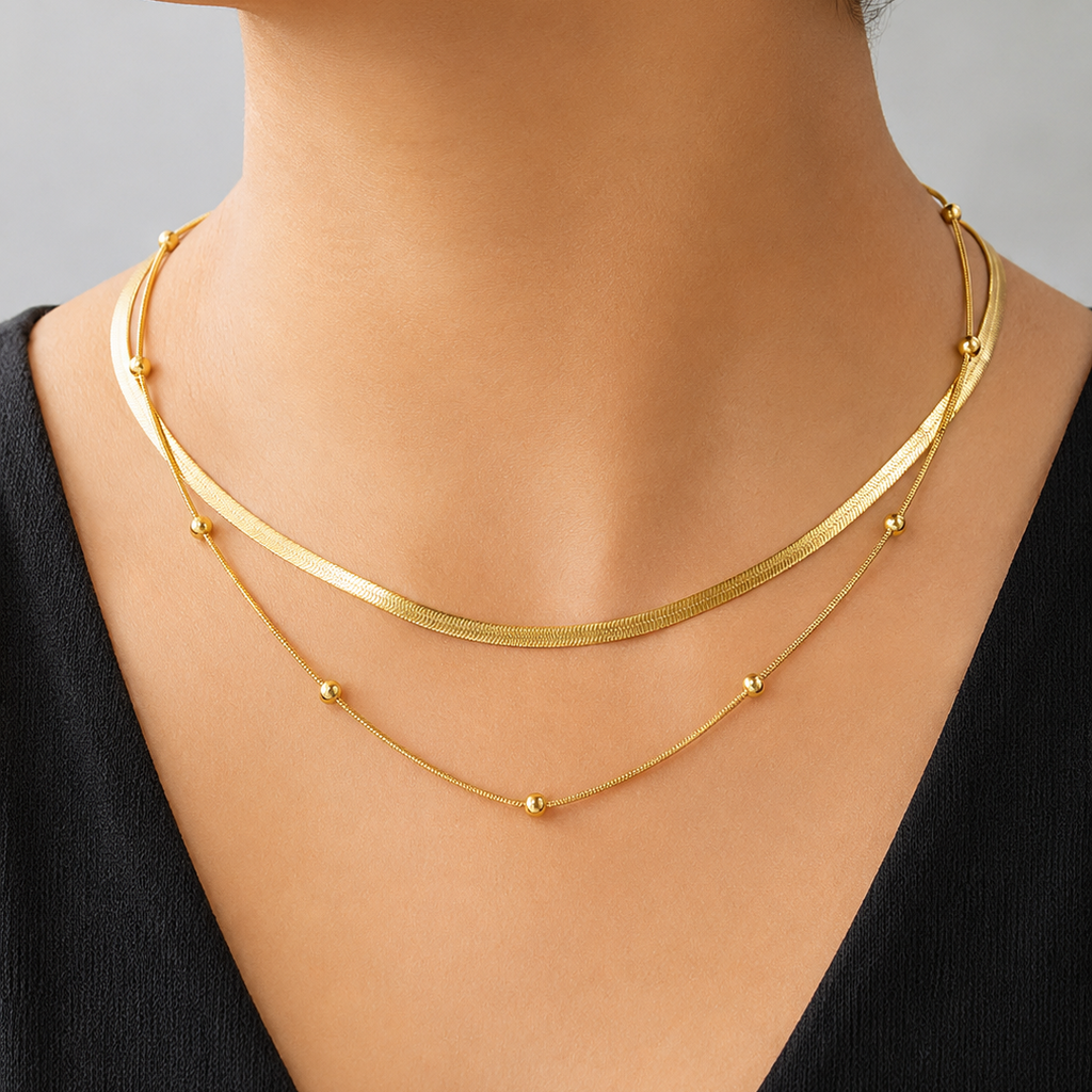 Gold tone necklaces on a mannequin with a plain background