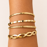 Golden bracelets on a wrist against a beige background