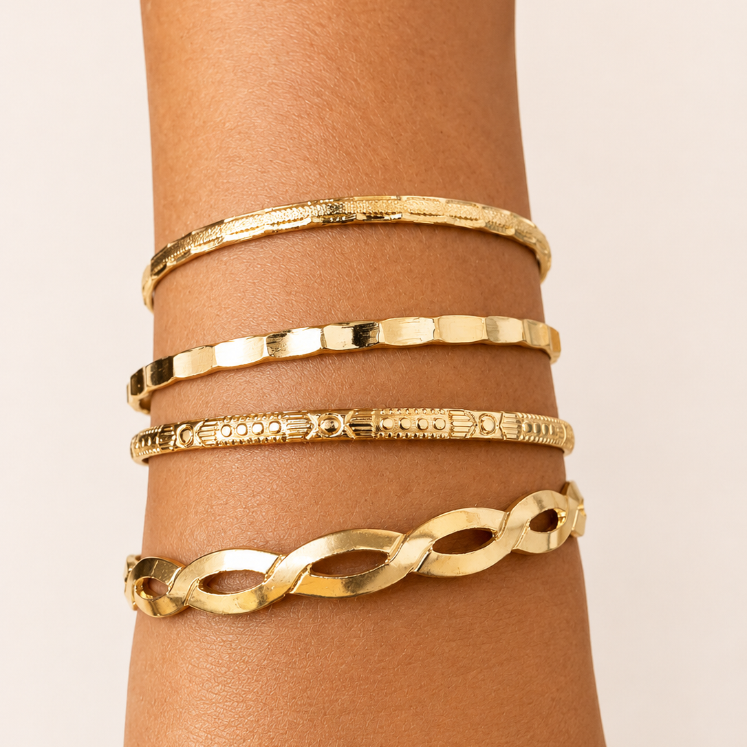 Golden bracelets on a wrist against a beige background