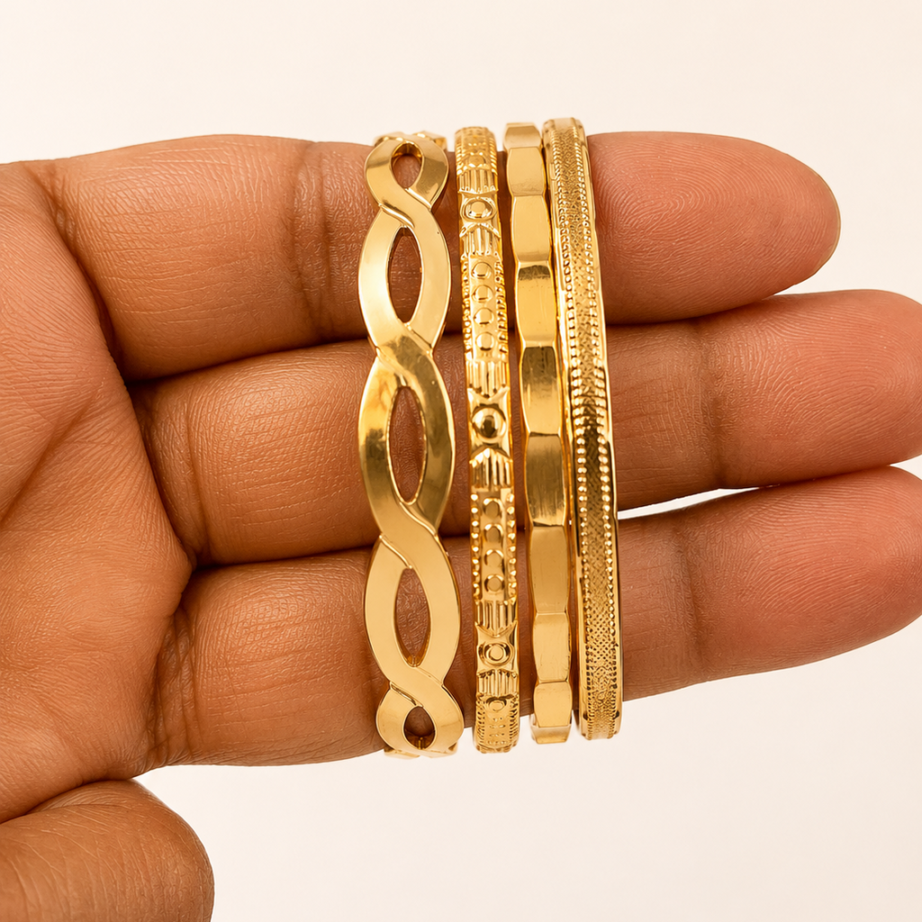 Golden bangles on a hand against a beige background