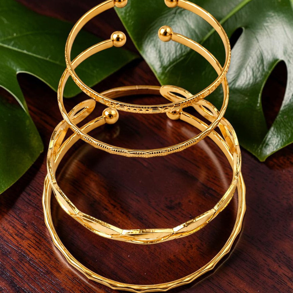 Golden bracelet on a wooden surface with green leaves in the background