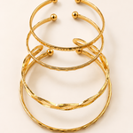 Stack of golden bracelets on a light beige background