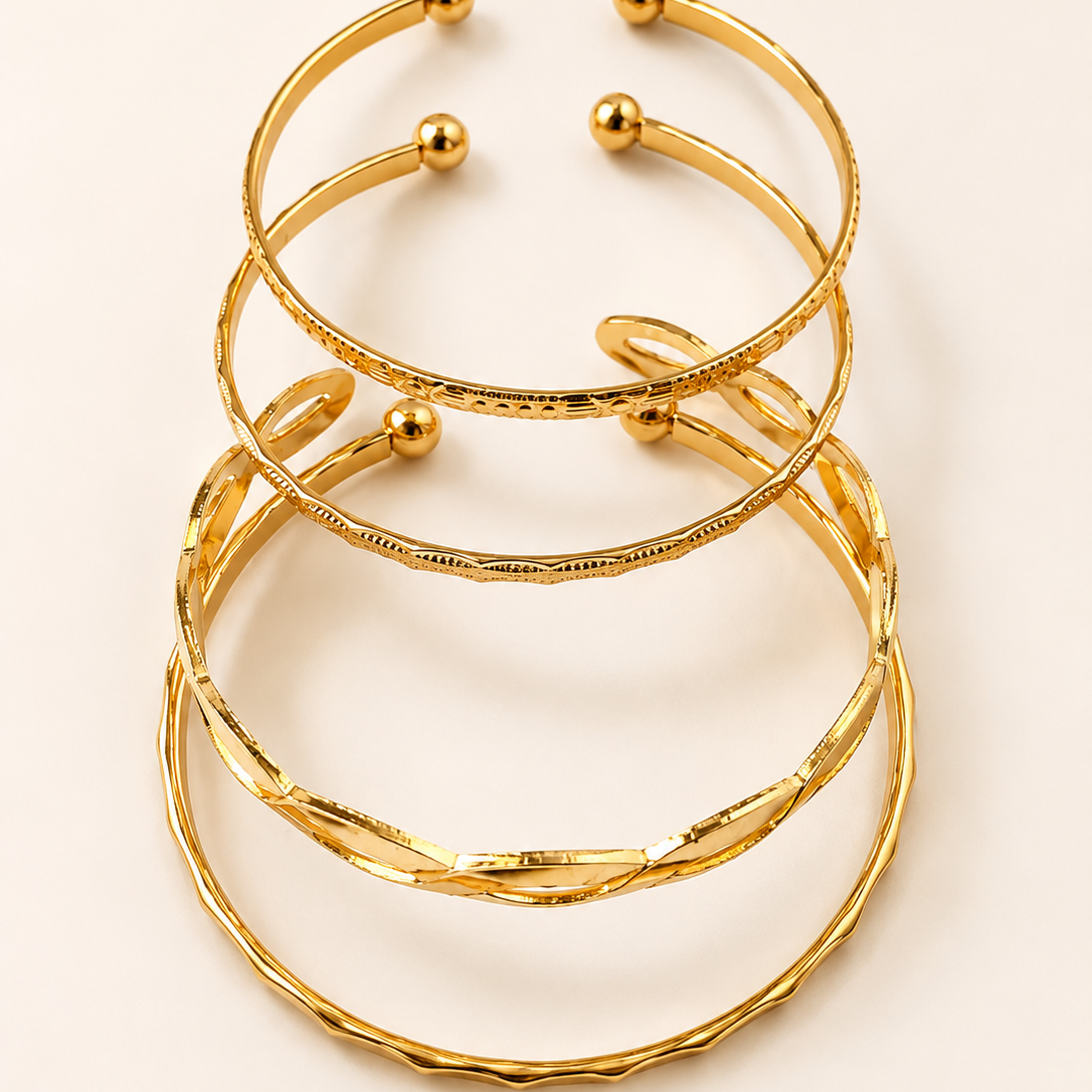 Stack of golden bracelets on a light beige background