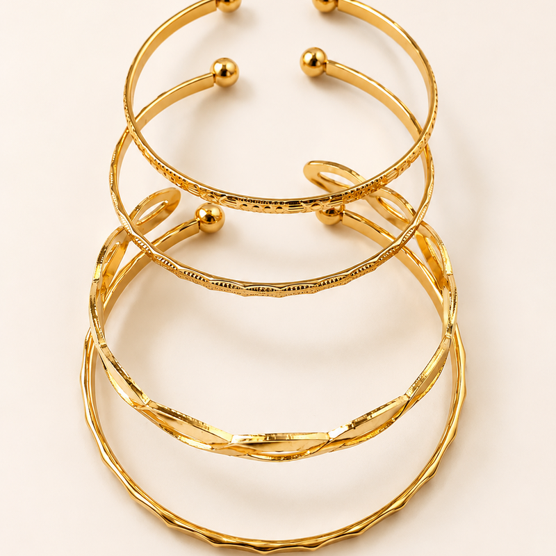 Stack of golden bracelets on a light beige background