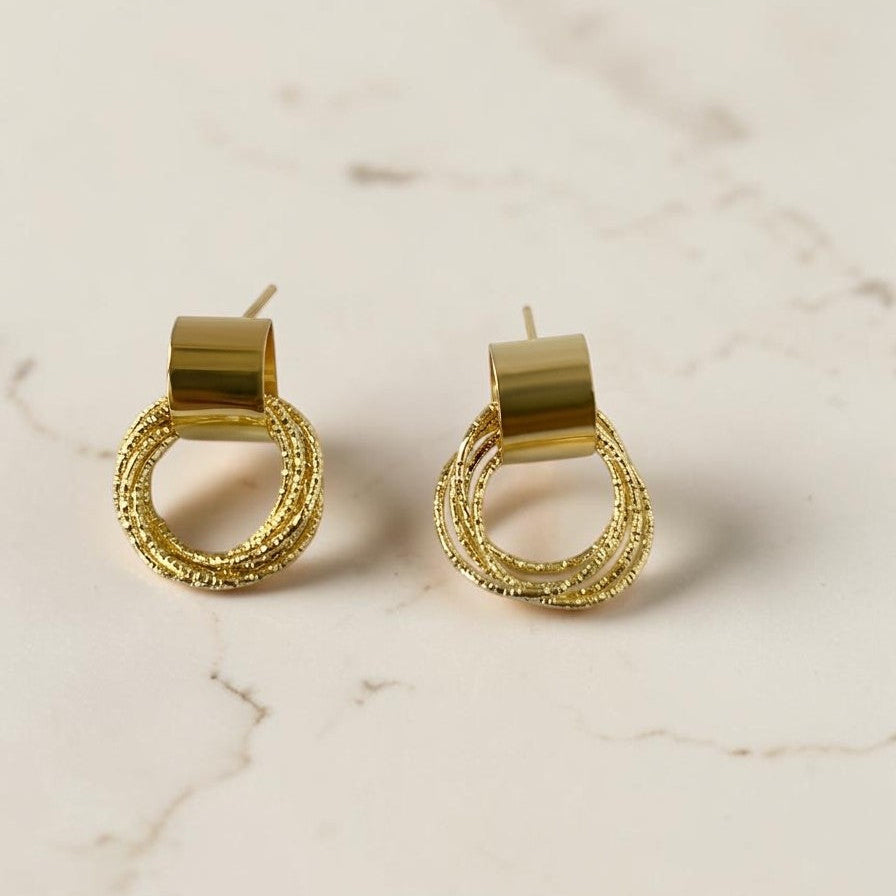 Gold hoop earrings on a marble surface