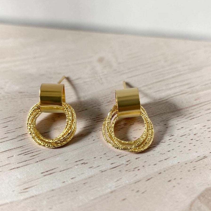 Gold hoop earrings on a light wooden surface