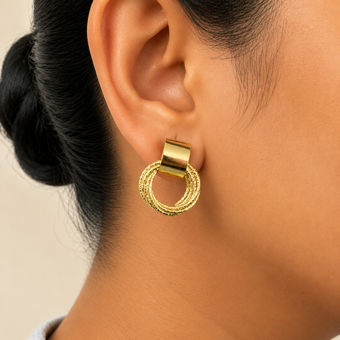 Gold hoop earring worn by a person with a neutral background