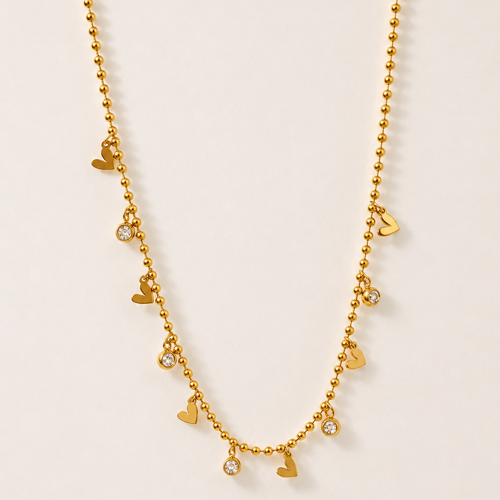 Gold tone necklace with heart-shaped charms on a beige background