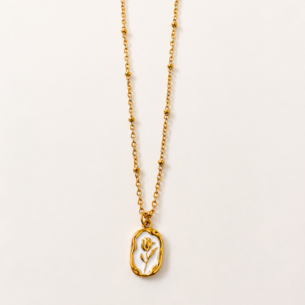 Gold tone necklace with a pendant on a light beige background