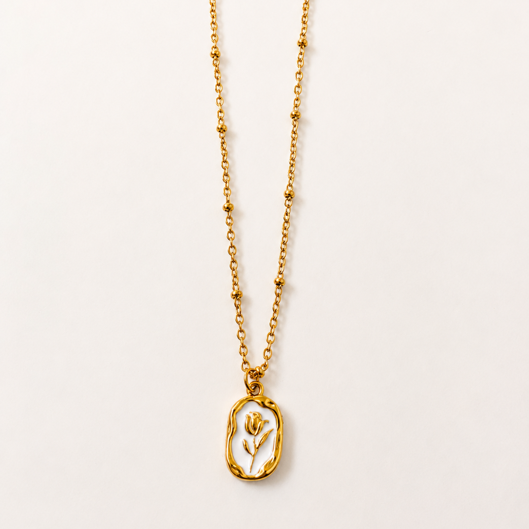 Gold tone necklace with a pendant on a light beige background