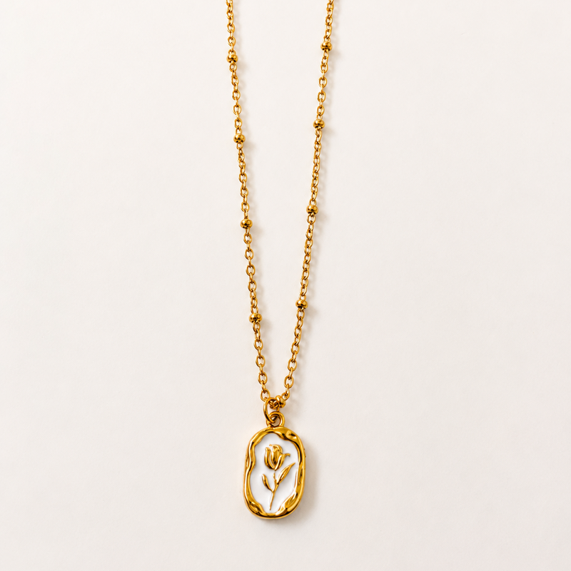 Gold tone necklace with a pendant on a light beige background
