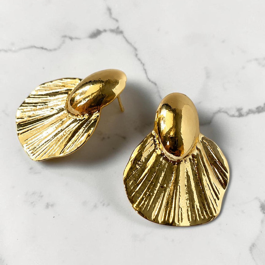 Gold tone earrings on a marble surface