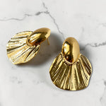 Gold tone earrings on a marble surface
