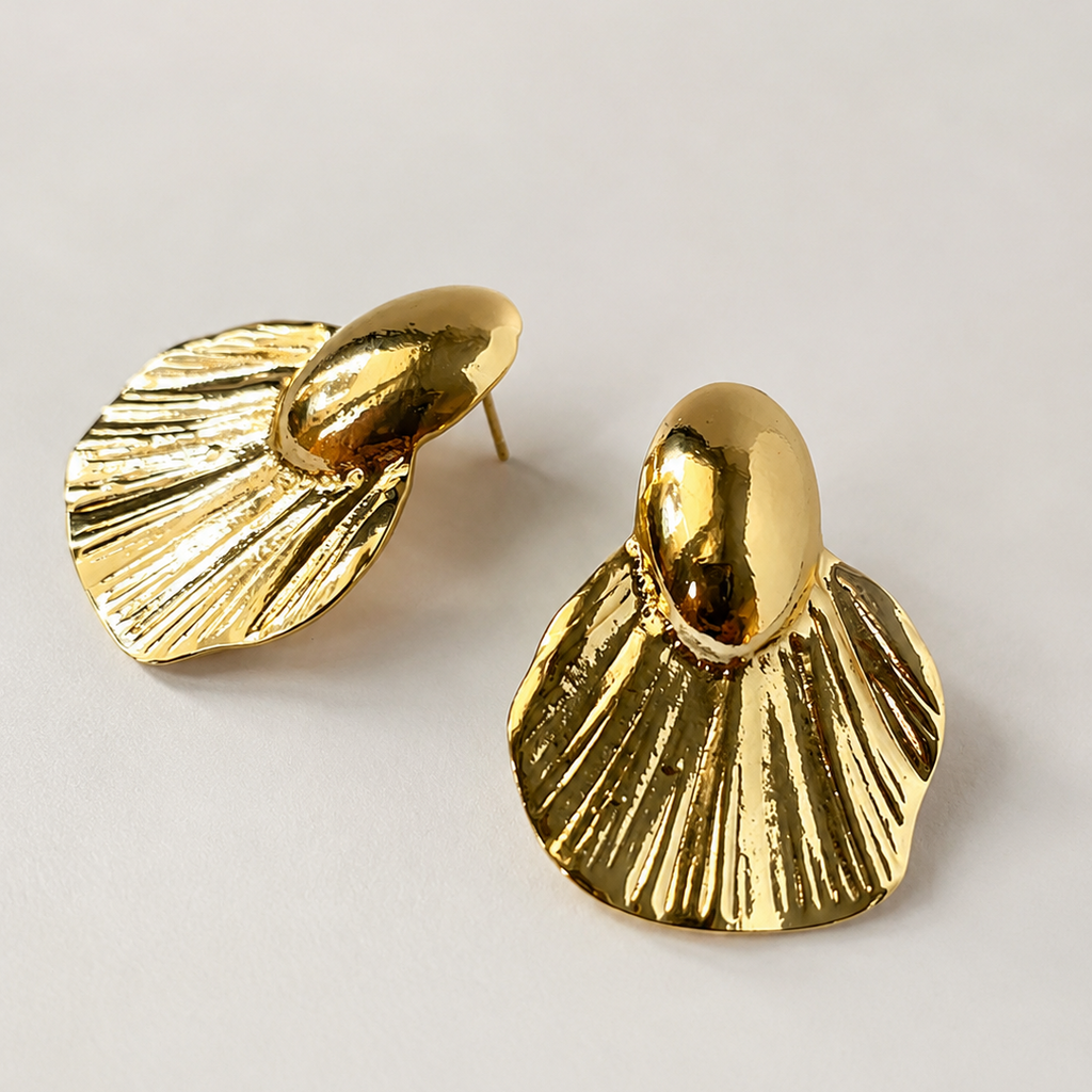 Pair of gold ton earrings on a light gray background