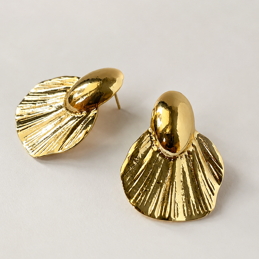 Pair of gold ton earrings on a light gray background