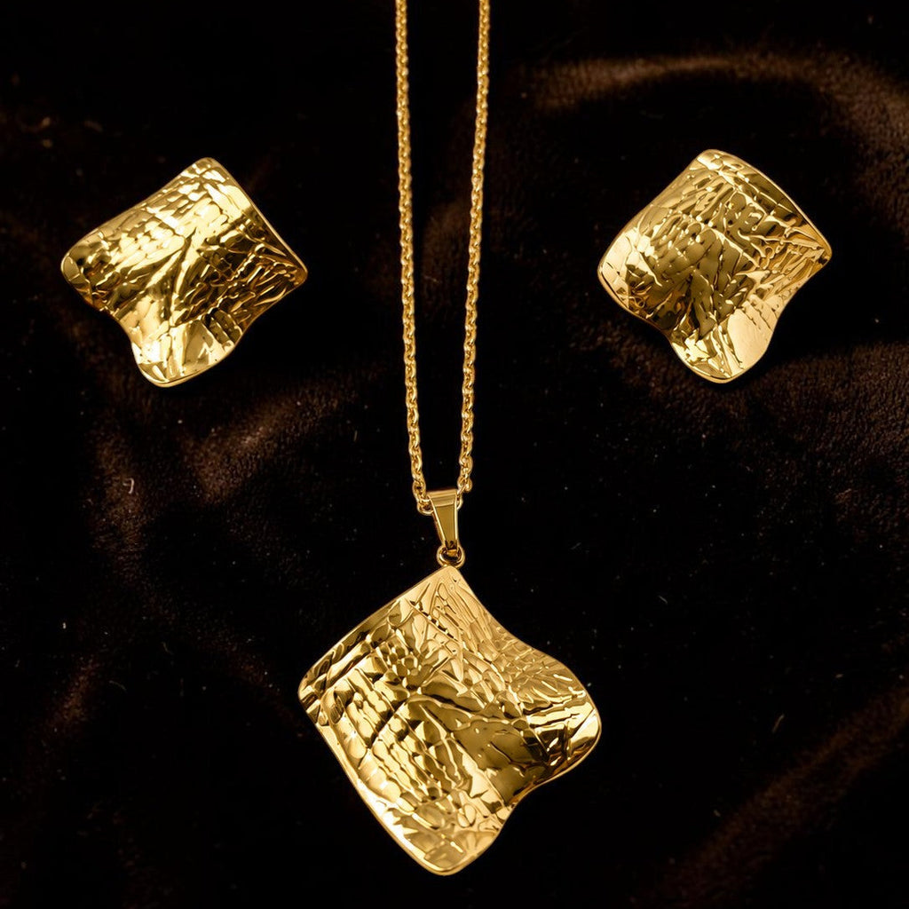 Gold tone necklace and earrings set on a dark background