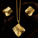 Gold tone necklace and earrings set on a dark background