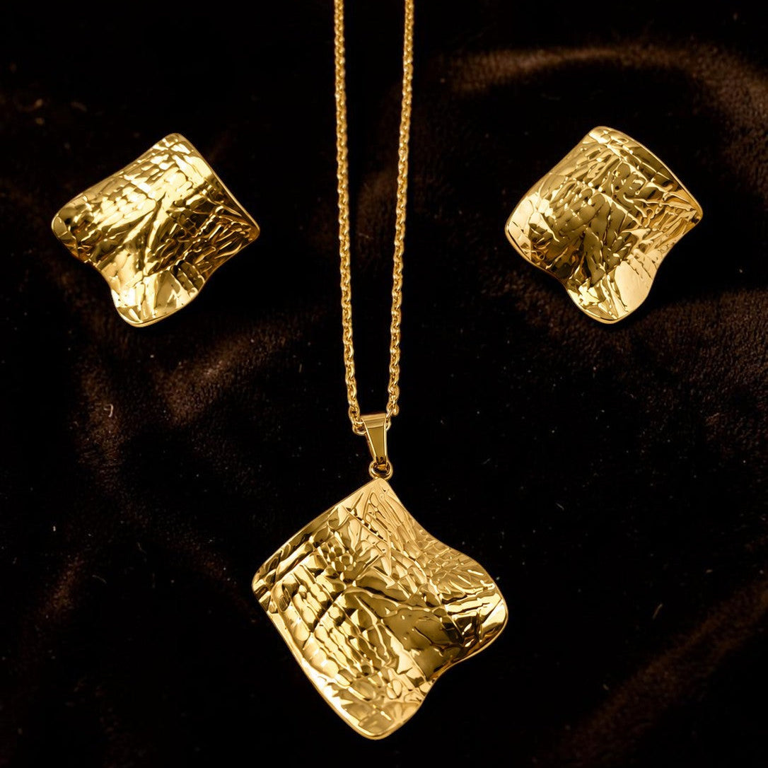 Gold tone necklace and earrings set on a dark background