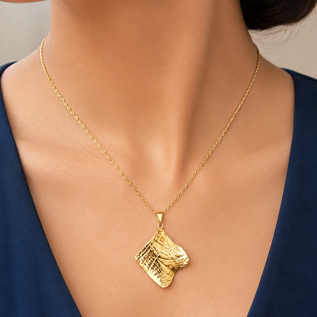 Gold tone necklace with a pendant on a model wearing a blue top